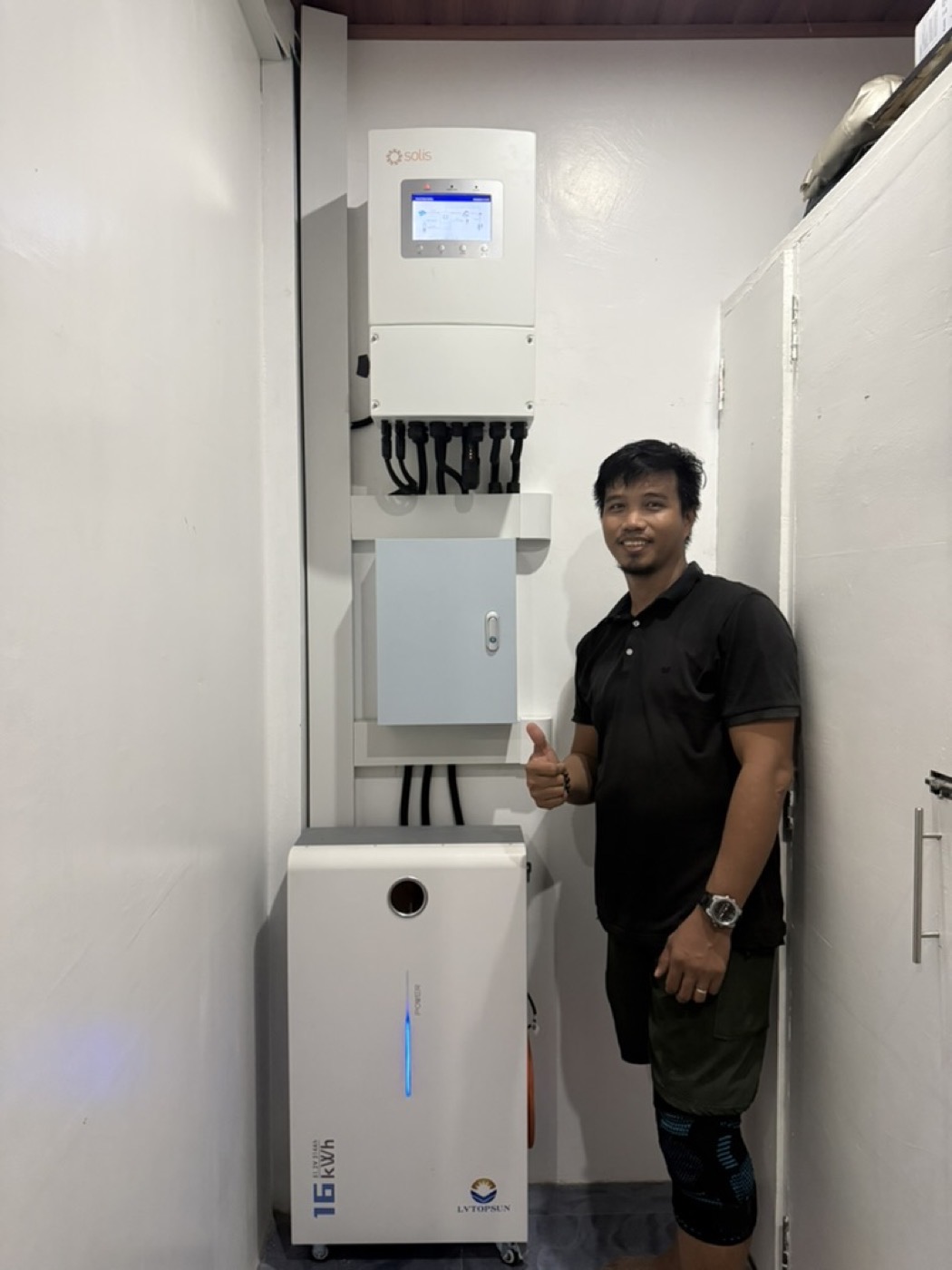 Technician standing beside a wall-mounted LiFePO4 home battery unit