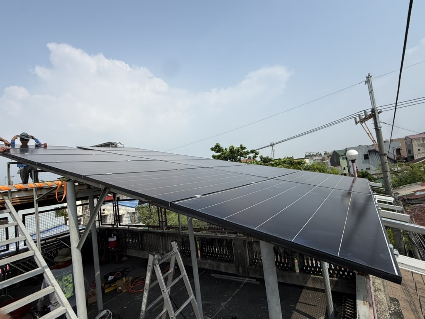 Rooftop solar array beside utility distribution lines, where a net-metered system connects to the grid
