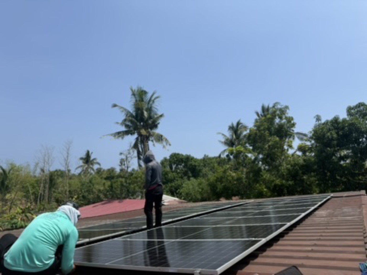 Installer kneeling on a roof to check and clean solar panels